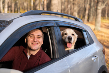 A young man and his dog sit in the car and look out the window. A young man with a golden retriever...