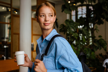 Ginger white woman drinking coffee while using cellphone at cafe