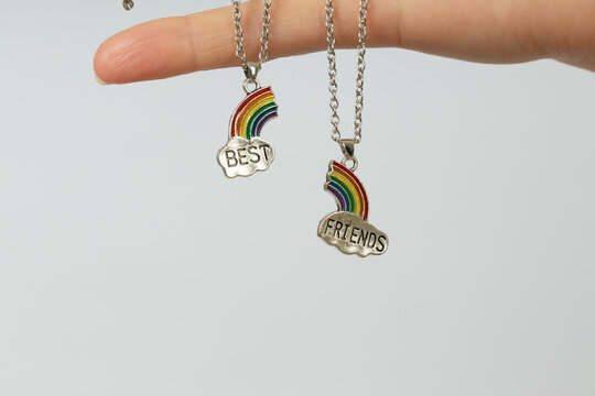 two pendants with silver clouds and halves of the rainbow with the inscription best friends on the palm