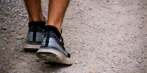 Close-up of feet in sport shoes walking on a stone path in the mountains.