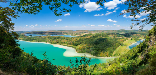 Fototapeta na wymiar Panorama depuis le célèbre belvédère des 4 Lacs dans le Jura en France. Les lacs turquoises contrastent avec les forêts qui commencent à revêtir les couleurs de l'automne