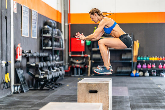 Sportswoman jumping on box in gym