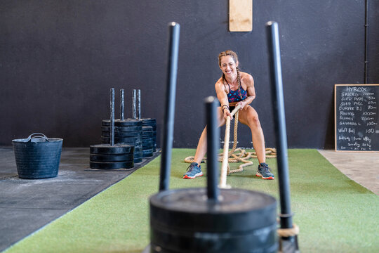 Happy sportswoman exercising with weight sled