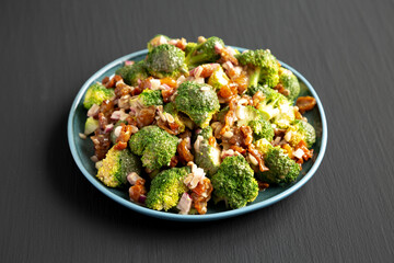 Homemade Broccoli Bacon Salad on a Plate on a black background, side view.