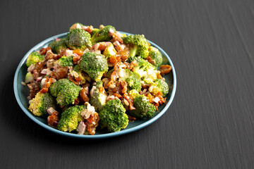 Homemade Broccoli Bacon Salad on a Plate on a black background, side view. Space for text.
