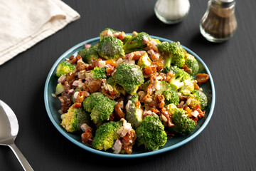 Homemade Broccoli Bacon Salad on a Plate on a black background, side view.