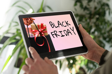 man searching website internet store to purchase gifts online in Black Friday with your tablet in you home, hands of a man at a website with an announcement concept for black friday deals