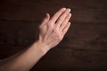 The praying hands of a man on a wooden background. The Concept of Religion.