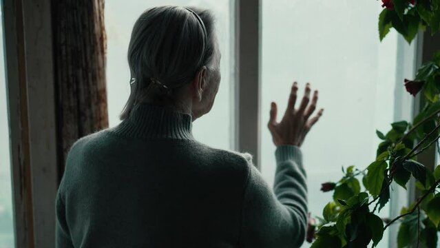 Old woman looking outside the window