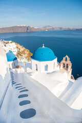 Beautiful Oia town on Santorini island, Greece. Traditional white architecture and greek orthodox churches with blue domes over the Caldera, Aegean sea. Scenic travel