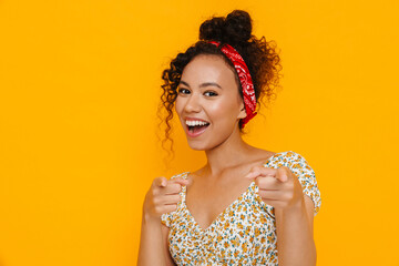 Curly brunette woman smiling and pointing fingers at camera