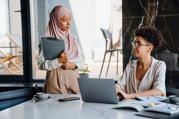 Middle-aged businesswoman and her female assistant working in office