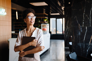 Happy businesswoman smiling and holding laptop in office lobby