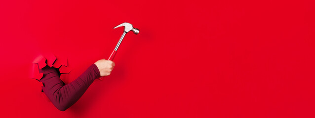 hammer in hand over red background, panoramic layout