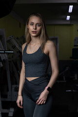 Fototapeta na wymiar Portrait of a young beautiful blonde girl in sportswear in the gym.