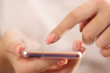 Female hands holding modern smartphone in hands and pointing on screen with finger