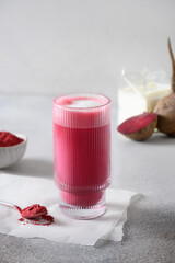Beetroot latte or pink moon milk latte of beetroot powder in glass on white background. Trendy healthy vegan and caffeine free drink. Vertical format. Close up.