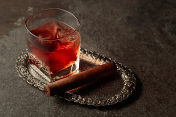 Whiskey with ice and cigar on an old stone table.