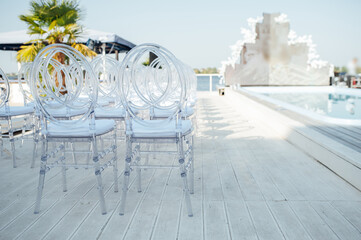 Glass chairs stand in a row in a beautiful wedding outing ceremony