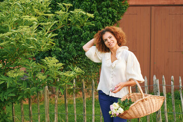 Outdoor portrait of beautiful 50 year old woman enjoying nice day in flower park or garden, happy...