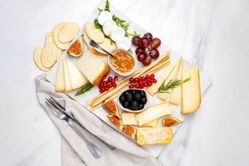 Cheese plate with soft and hard cheeses brie, camembert, pecorino, goat cheese with jam olives and berry and crackers.