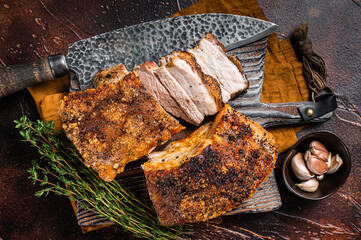 Roasted Pork belly bacon with crust on a wooden board. Dark background. Top view