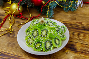 Christmas tree shaped fruit salad and Christmas decorations on wooden table. Creative idea for Christmas and New Year festive desserts. Funny food idea for kids