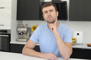 Suspicious looking man thinking in the kitchen 