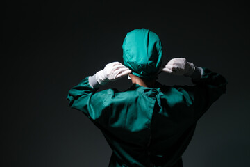 Female doctor surgeon wearing scrub overall suit for medical surgery clothing putting on rubber...