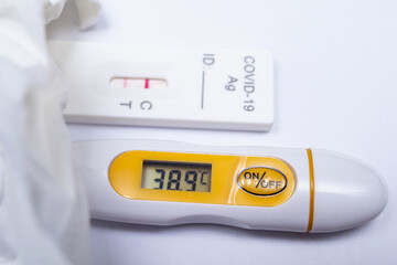 Termometr wskazujący wysoką temperaturę ciała i pozytywny wynik testu na obecność koronawirusa nie pozostawiają wątpliwości - to nie przeziębienie - obrazy, fototapety, plakaty