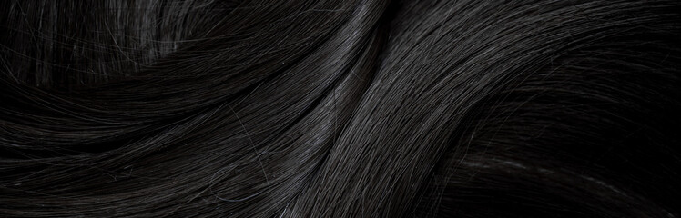 Brunette or black hair. Female long dark hair in black. Beautifully laid curls. Closeup texture in a dark key. Hairdressing, hair care and coloring. Shading gray hair. Background with copy space.