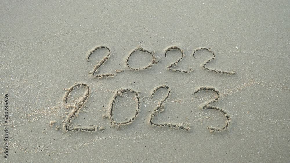 Wall mural message year 2022 replaced by 2023 written on beach sand background. goodbye 2022 hello to 2023 lapp