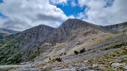 Panoramic view of the cloud covered slopes and rocky ridges of Pieria Mountains near Mount Olympus in Mt Olympus National Park, Thessaly, Greece, Europe. Trekking on hiking trail through mystical fog