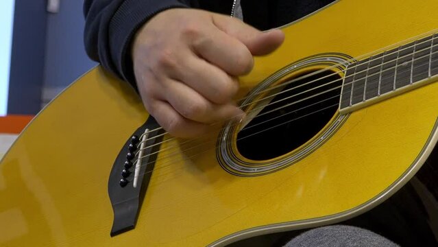 Playing an acoustic guitar in close-up. Guitar player's hands