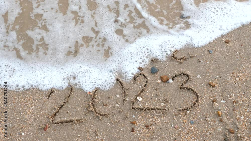 Wall mural message year 2022 replaced by 2023 written on beach sand background. goodbye 2022 hello to 2023 lapp