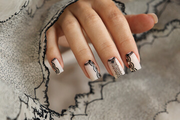 Nude manicure with graphic patterns and rhinestones on the square shape of nails.