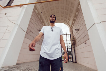 African american man in a white blank t-shirt walks down the street. Mock-up.