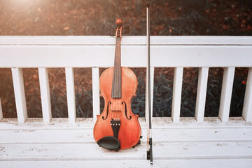 violin with a bow lies on a white bench