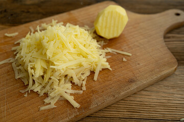 Raw Grated Potato on Wooden Cutting Board Top View