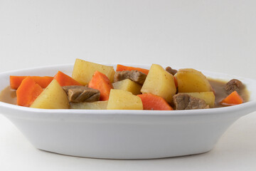 Portion of curry with potato, carrot and onion .
