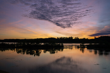 Fototapeta na wymiar Yellow sunrise in the lake behind the forest