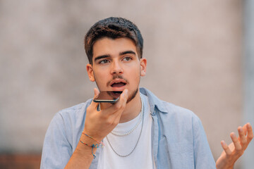 young man sending voice message on the street
