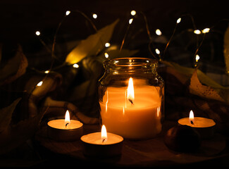 Autumn composition with burning candleson a dark background. Romantic atmosphere. Halloween...