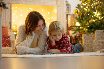 Cute child, boy, sitting on a yellow armchair in a decorated room for Christmas