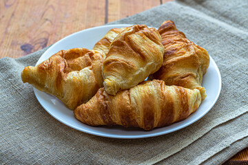 White plate with fresh croissants on a canvas tablecloth
