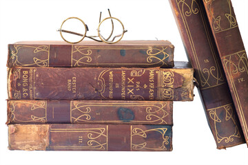 Pile of old books with vintage glasses, isolated on a white background