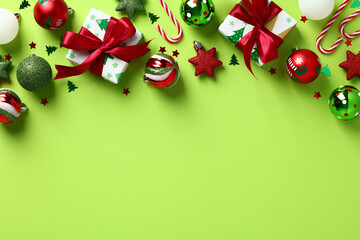 Stylish Christmas ornaments and gift boxes frame top border. Xmas decorations on pastel green background. Top view, flat lay.