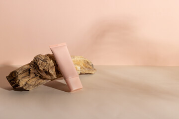 Face and body skin care products on a beige background next to a wooden branch. Professional cosmetics for skin care. Organic cosmetics. Cosmetics for women with natural ingredients. Copy space