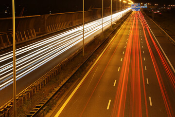 Autostrada samochodowa nocą ze smugami po przejeżdżających pojazdach.  - obrazy, fototapety, plakaty