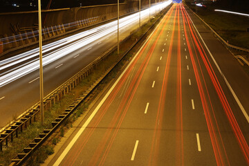 Autostrada samochodowa nocą ze smugami po przejeżdżających pojazdach. 